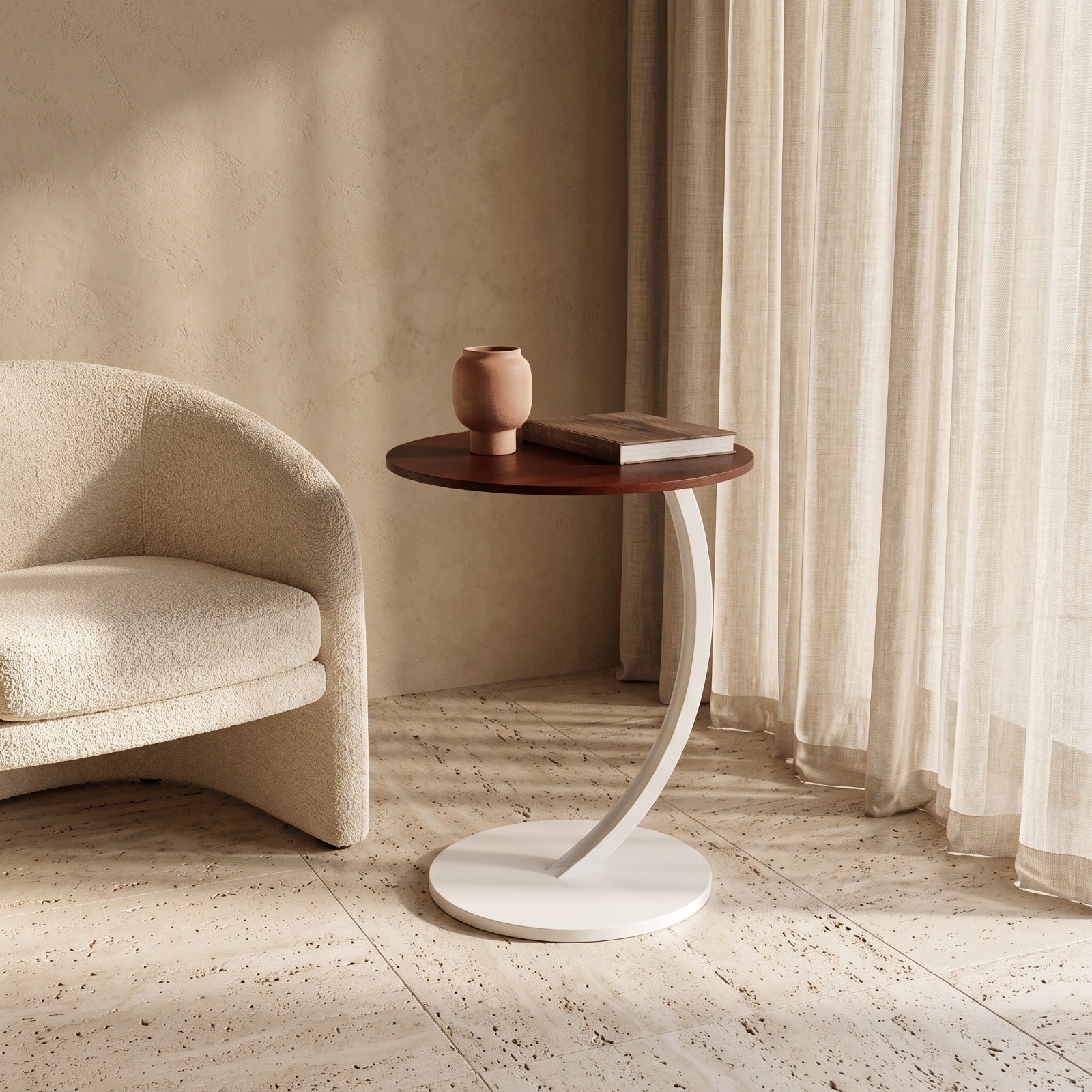A modern side table with a round dark wood top and a curved white metal base, styled in a warm, minimalist room next to a cream bouclé armchair.