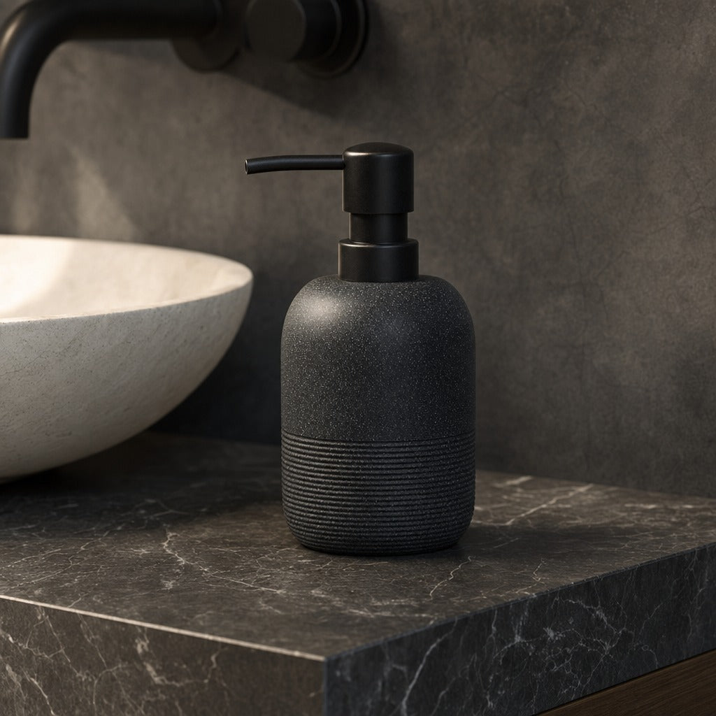 A matte black textured soap dispenser with a ribbed base and a black pump, shown on a dark marble countertop next to a white vessel sink.