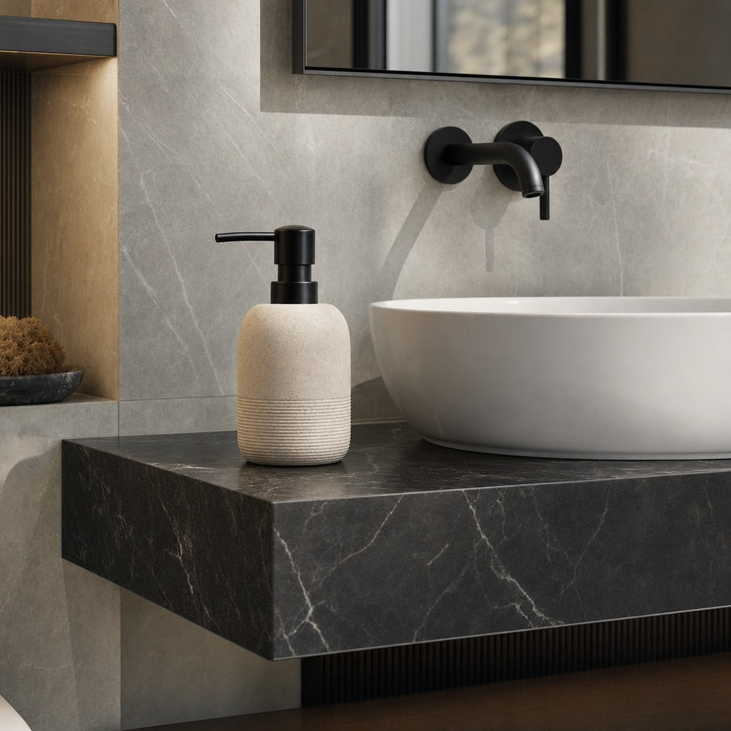 A modern bathroom scene featuring a textured cream soap dispenser with a black pump, set on a floating dark gray marble countertop next to a white vessel sink and matte black faucet.