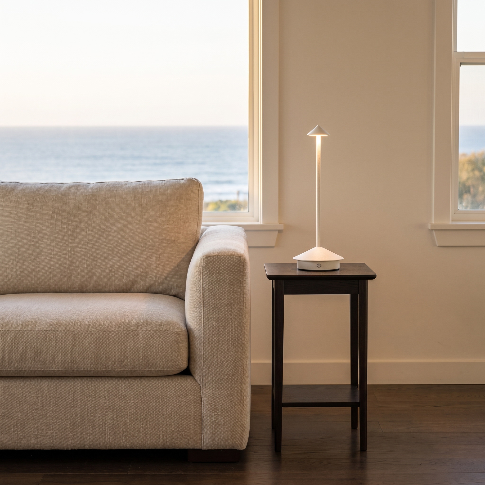 Amalfi portable table lamp in white on a living-room side table with an ocean view