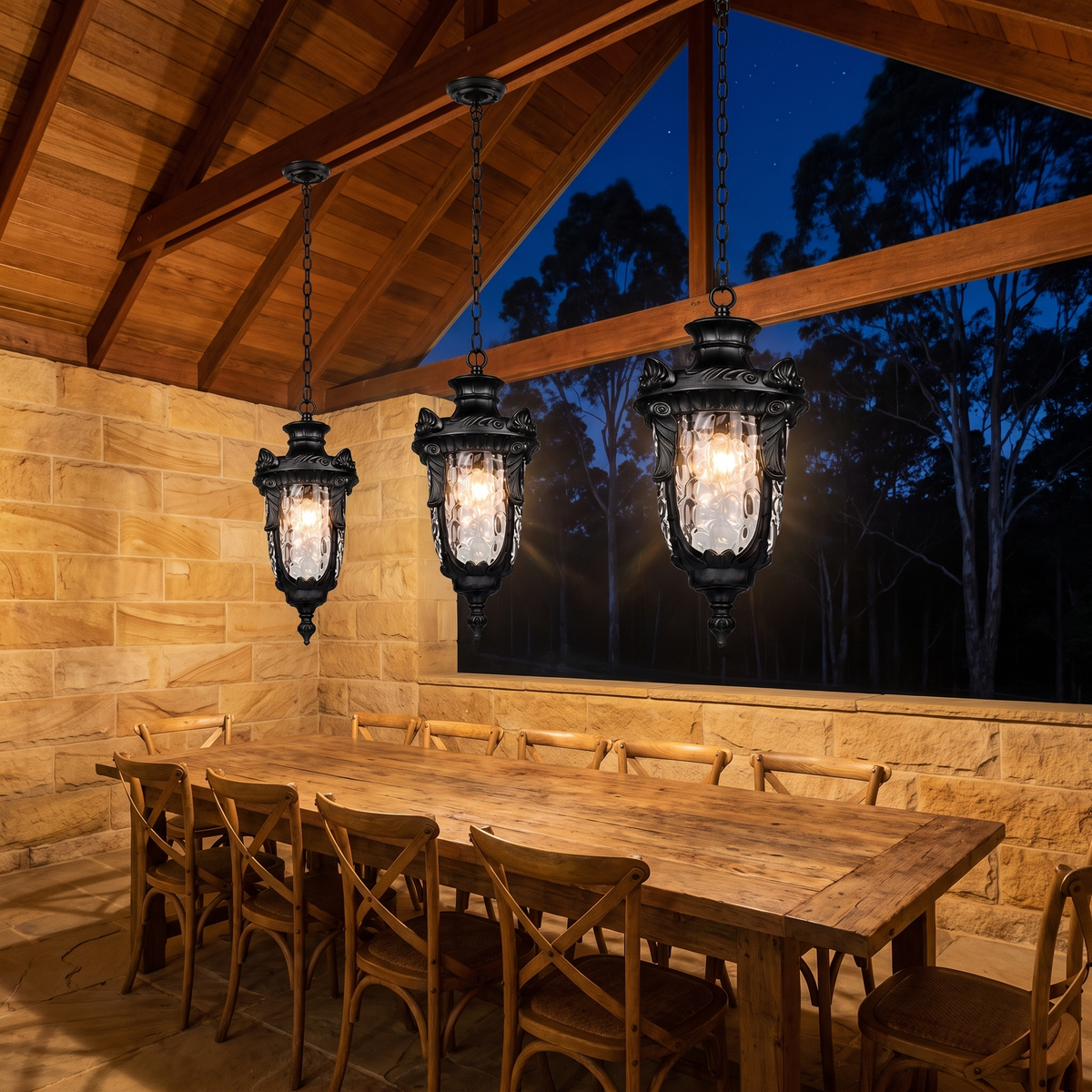 Three Anita outdoor pendants in black glowing over a rustic table in a sandstone alfresco at night