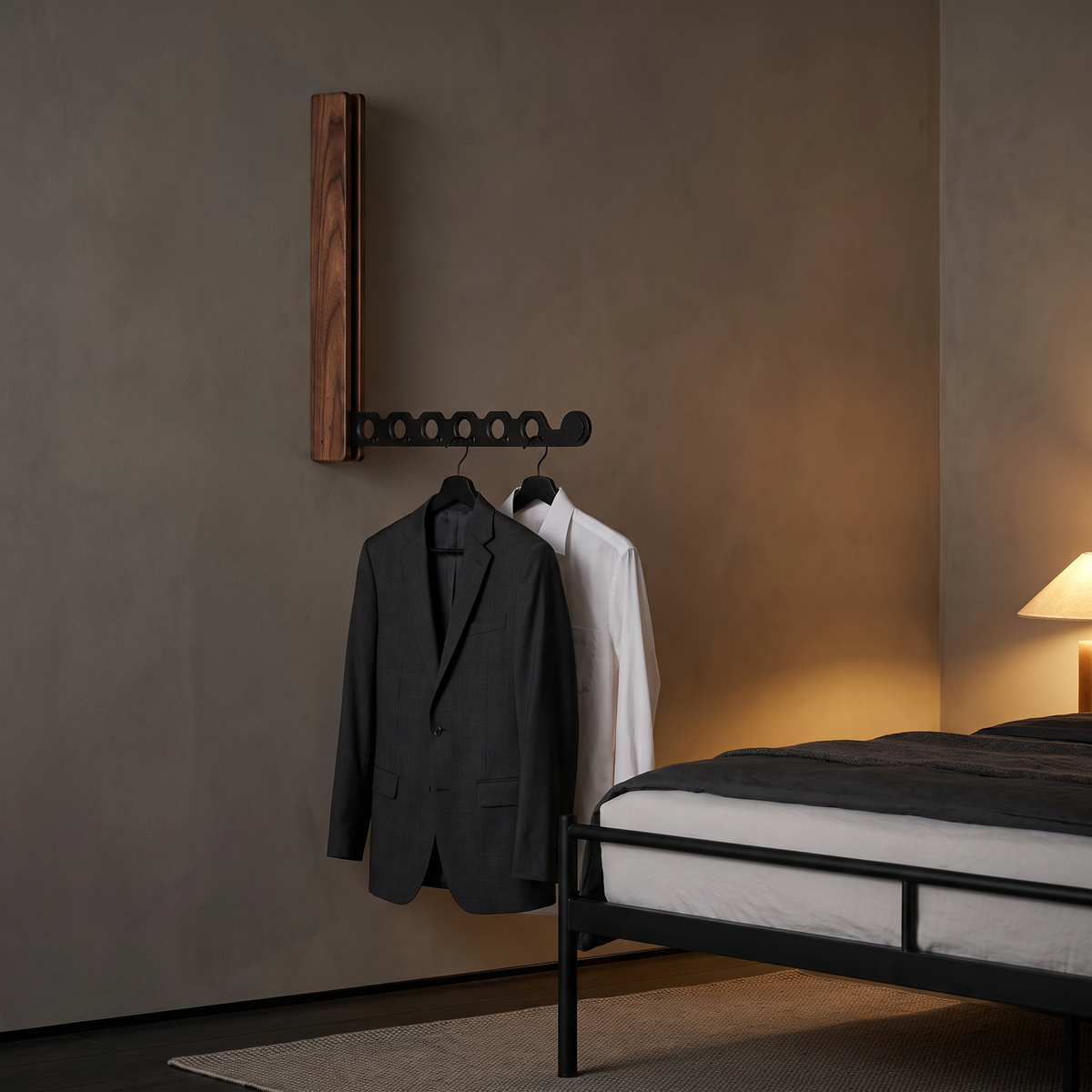 Arnie timber hanger rail in black walnut holding a suit jacket and shirt in an evening bedroom