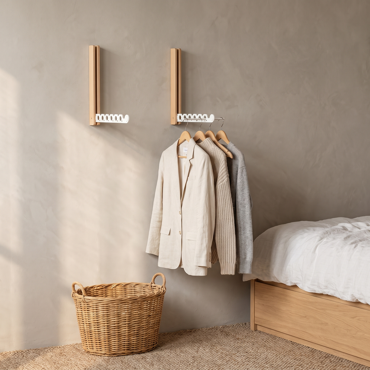 A set of two Arnie timber hanger rails in white airing a linen blazer and knits in a Scandinavian bedroom
