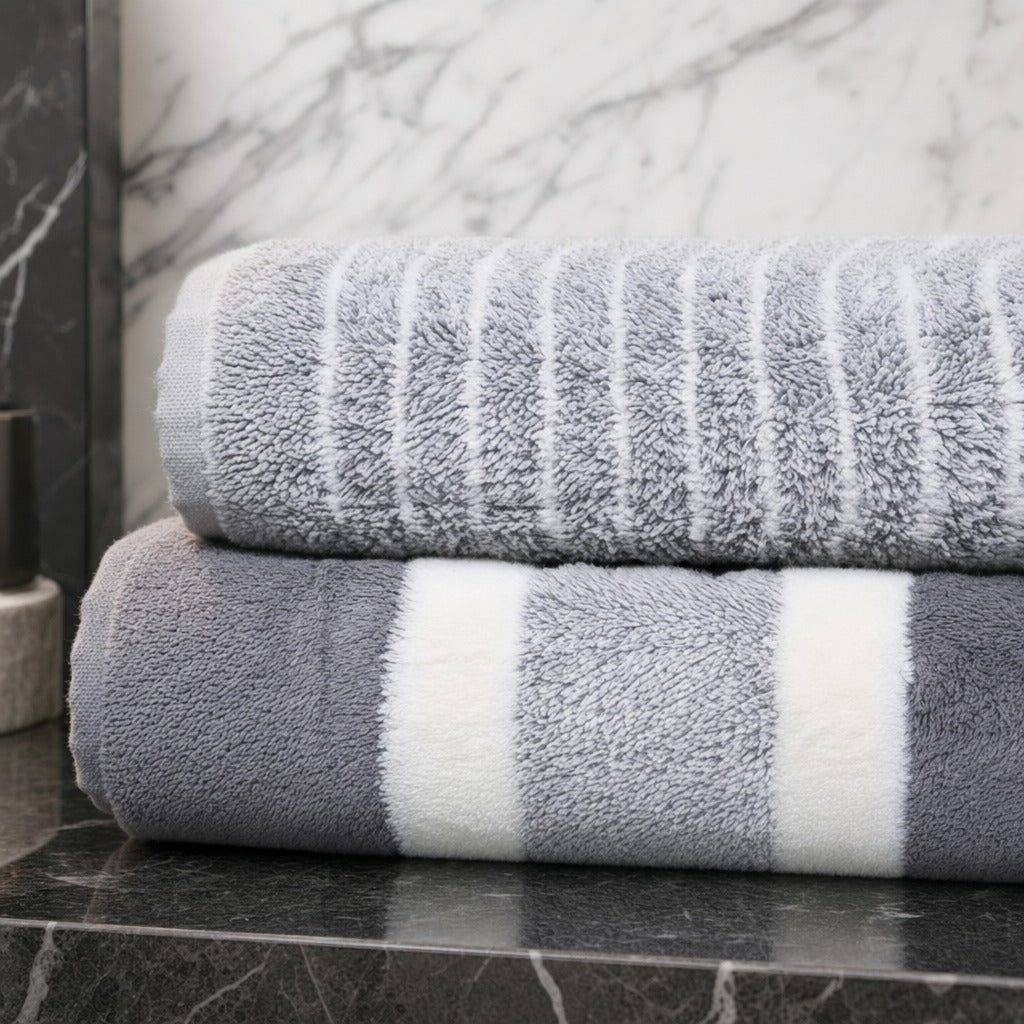 Folded grey Aurelia microfibre bath towels with white stripes on a dark marble benchtop