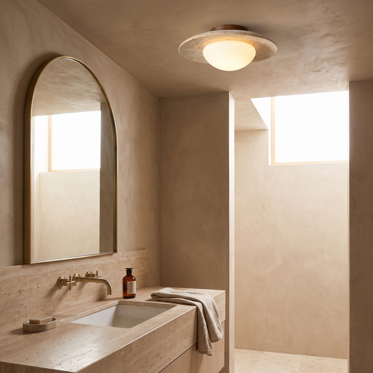 Bali travertine ceiling light in a stone ensuite bathroom with brushed brass tapware