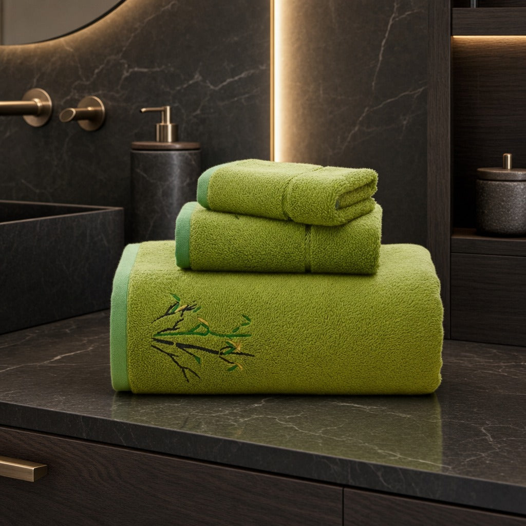 Bamboo face and bath towel set in green stacked on a dark stone bathroom vanity