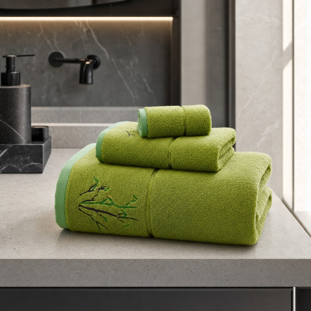 Bamboo bath, hand and face towels in green on a grey stone vanity beside a black tap