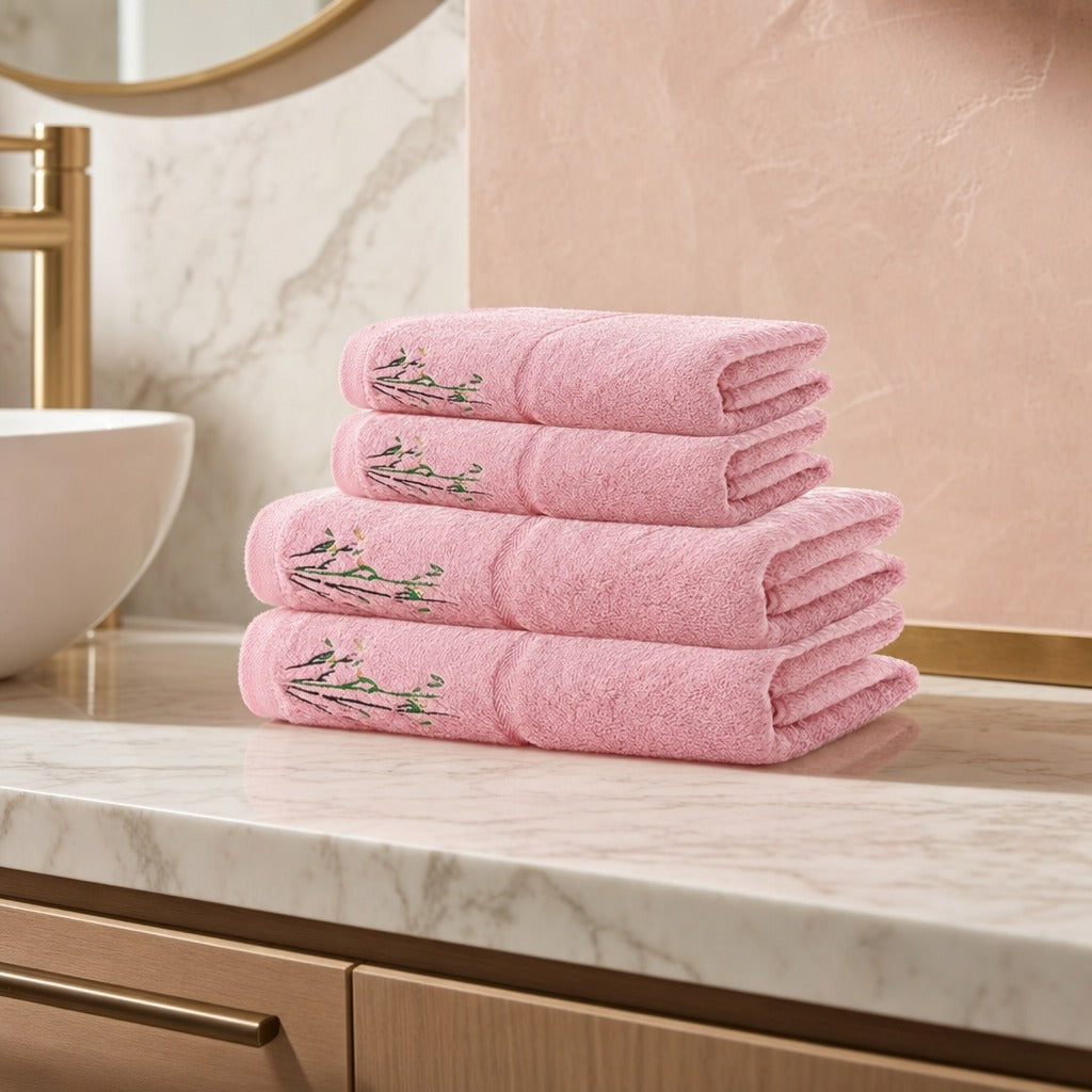 Bamboo face and bath towel set in pink stacked on an oak vanity against a marble wall