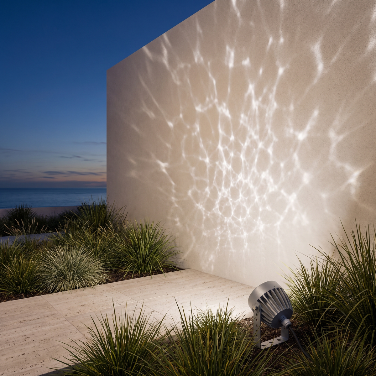 Beso water ripple outdoor spotlight casting a cool white ripple effect across a coastal home wall at dusk