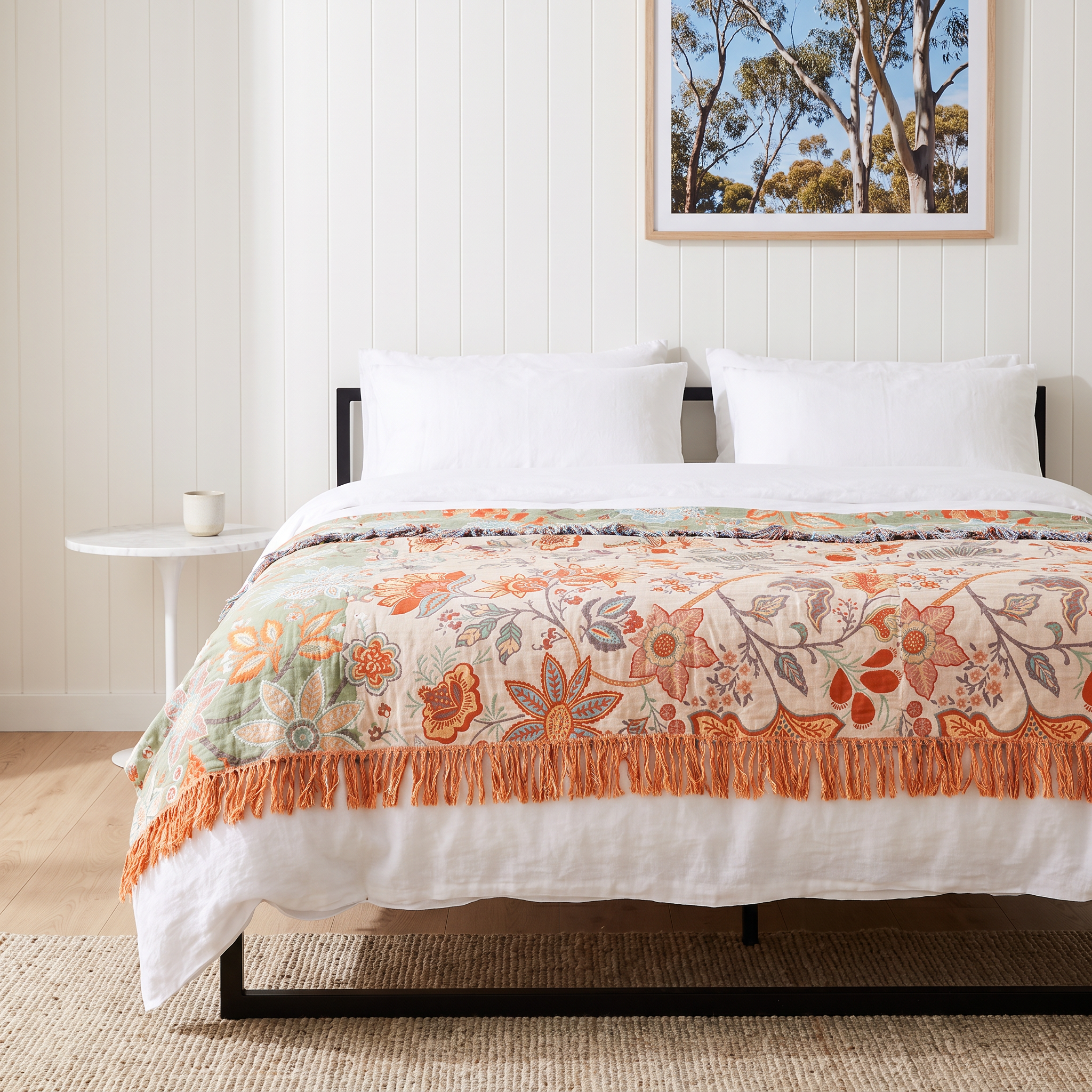Bliss floral cotton throw blanket on a black metal bed frame in a white shiplap beach house bedroom