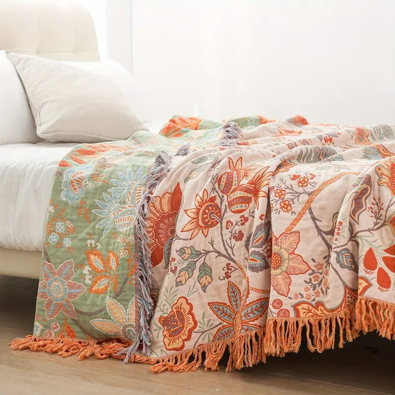 Bliss floral cotton throw blanket in orange and blue on a soft cream ground