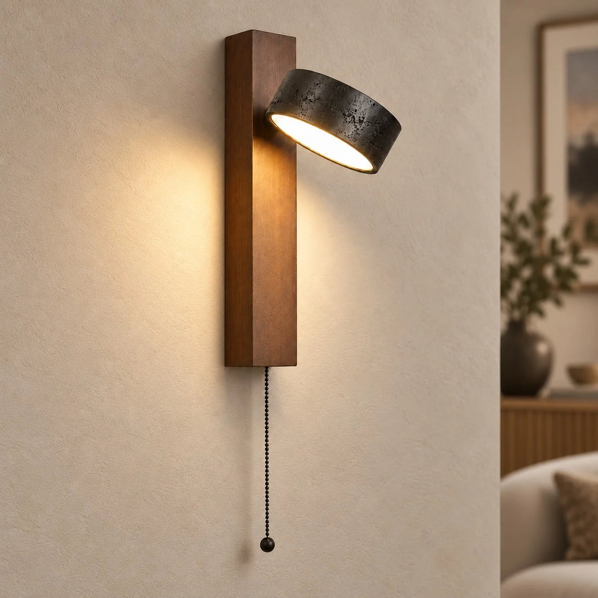 Boa pull chain wall sconce with walnut base and black travertine head lit on a plaster wall