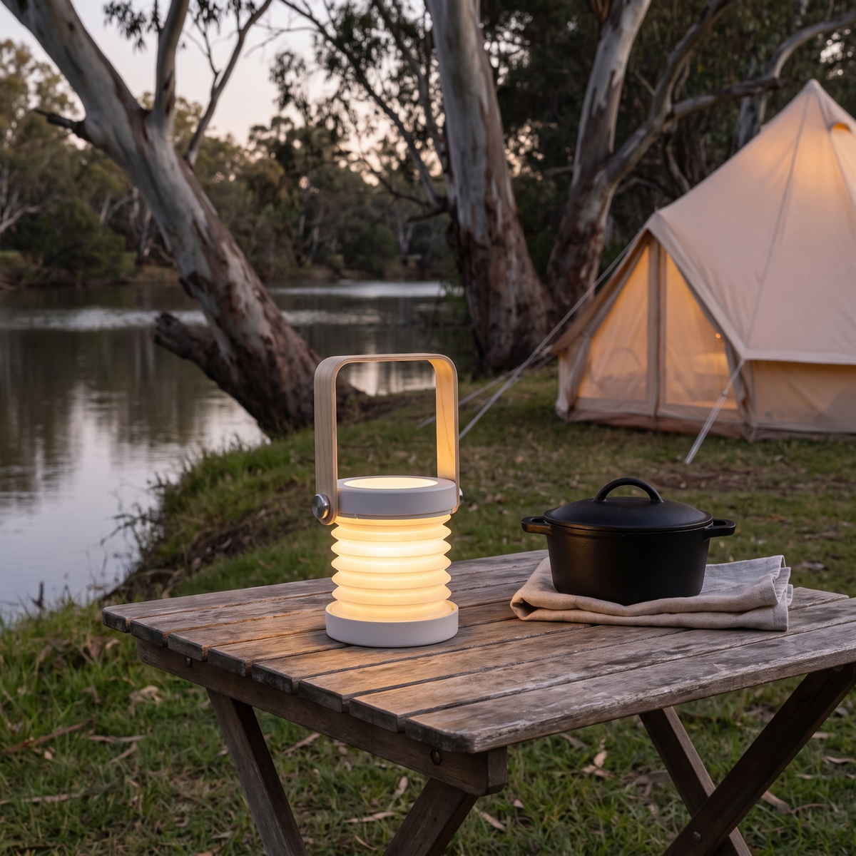 Brae folding travel lantern in grey on a camp table at a riverside bush camp at twilight