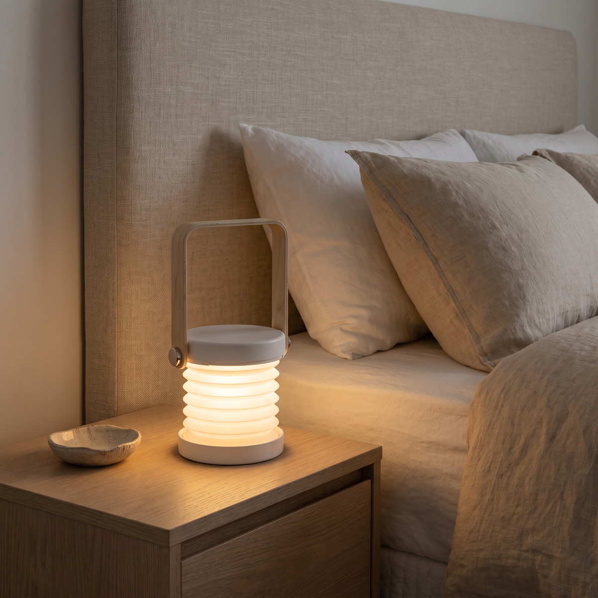 Brae rechargeable lantern in white used as a cordless bedside lamp on a timber bedside table at night