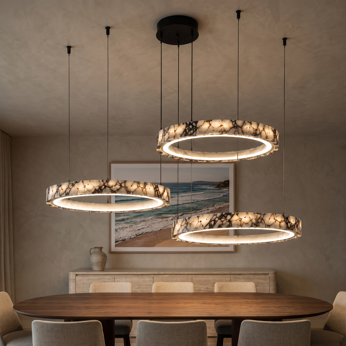 Byron three-ring marble chandelier glowing warm over a walnut dining table at night