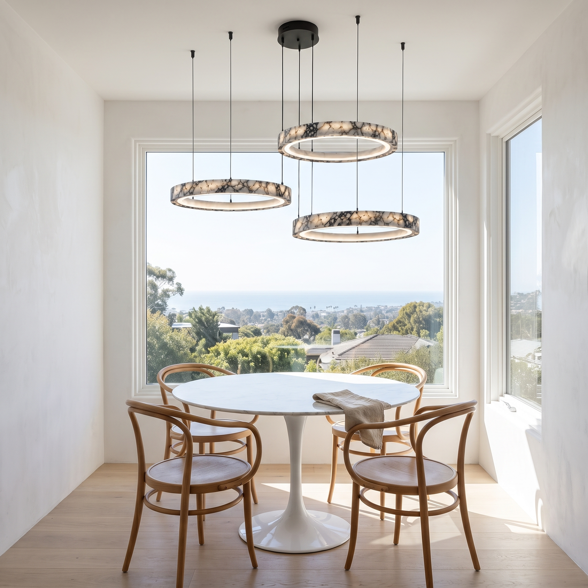 Byron three-ring marble chandelier over a round marble dining table with a hillside ocean view