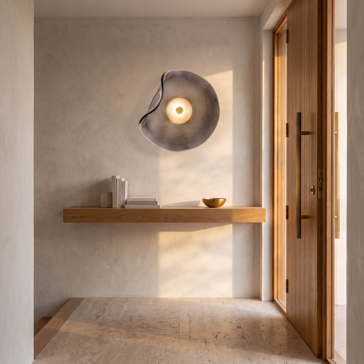 Cami glass wall sconce in smoke grey glass above a floating oak shelf in an entry foyer