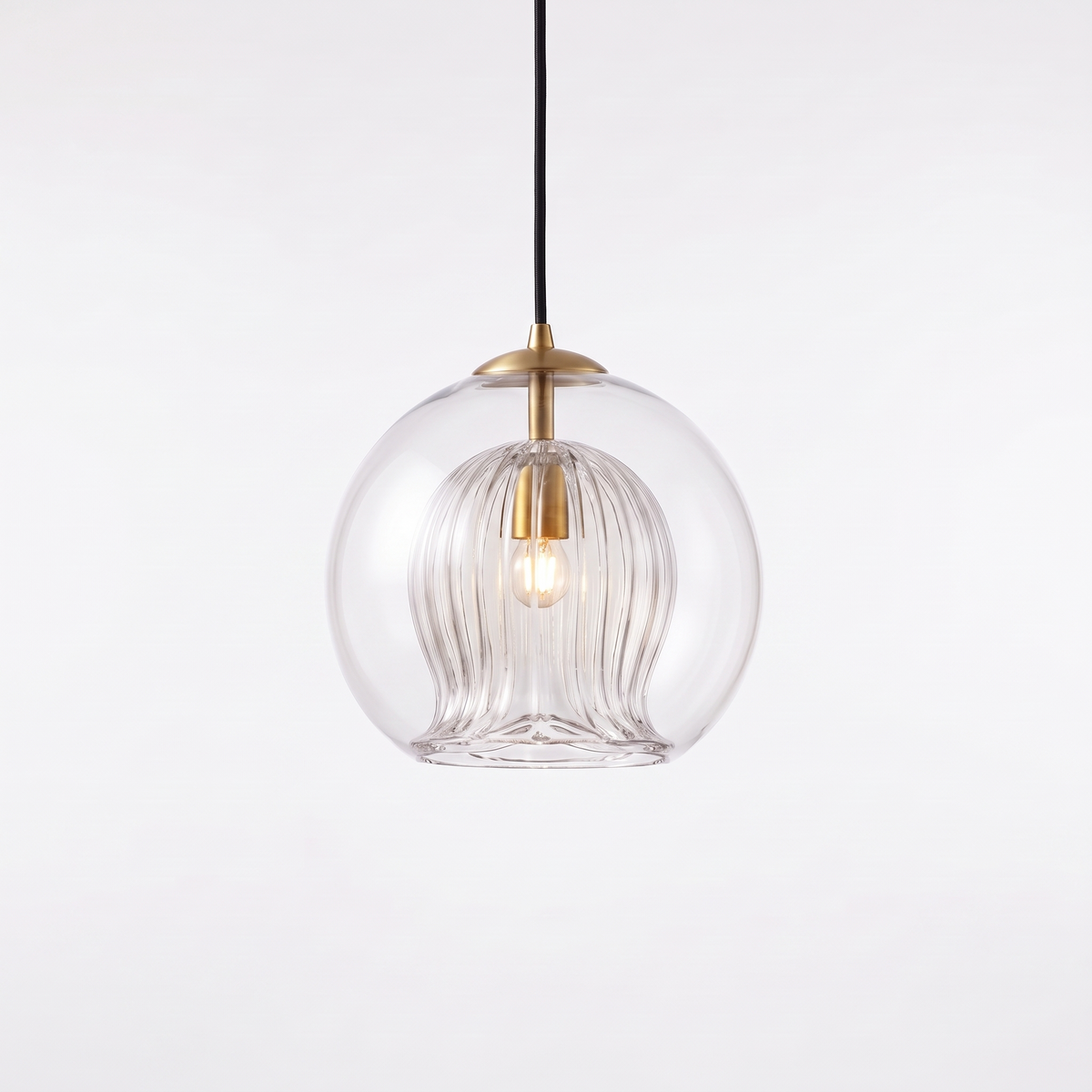 Capri clear glass pendant light with fluted inner shade and brass cap on a white background