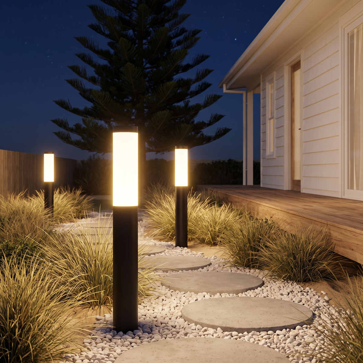 Three 61cm Clancy waterproof bollard lights glowing on a stepping-stone path to a beach house at night