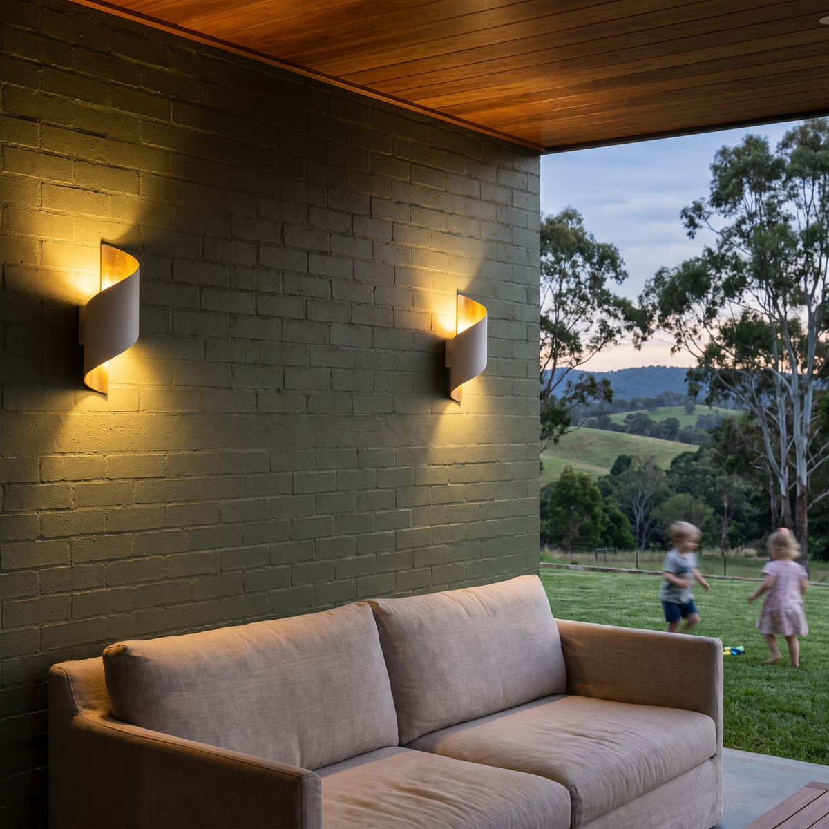 Two Clarry Outdoor Wall Lights in white and gold on olive brick in a hinterland alfresco at dusk