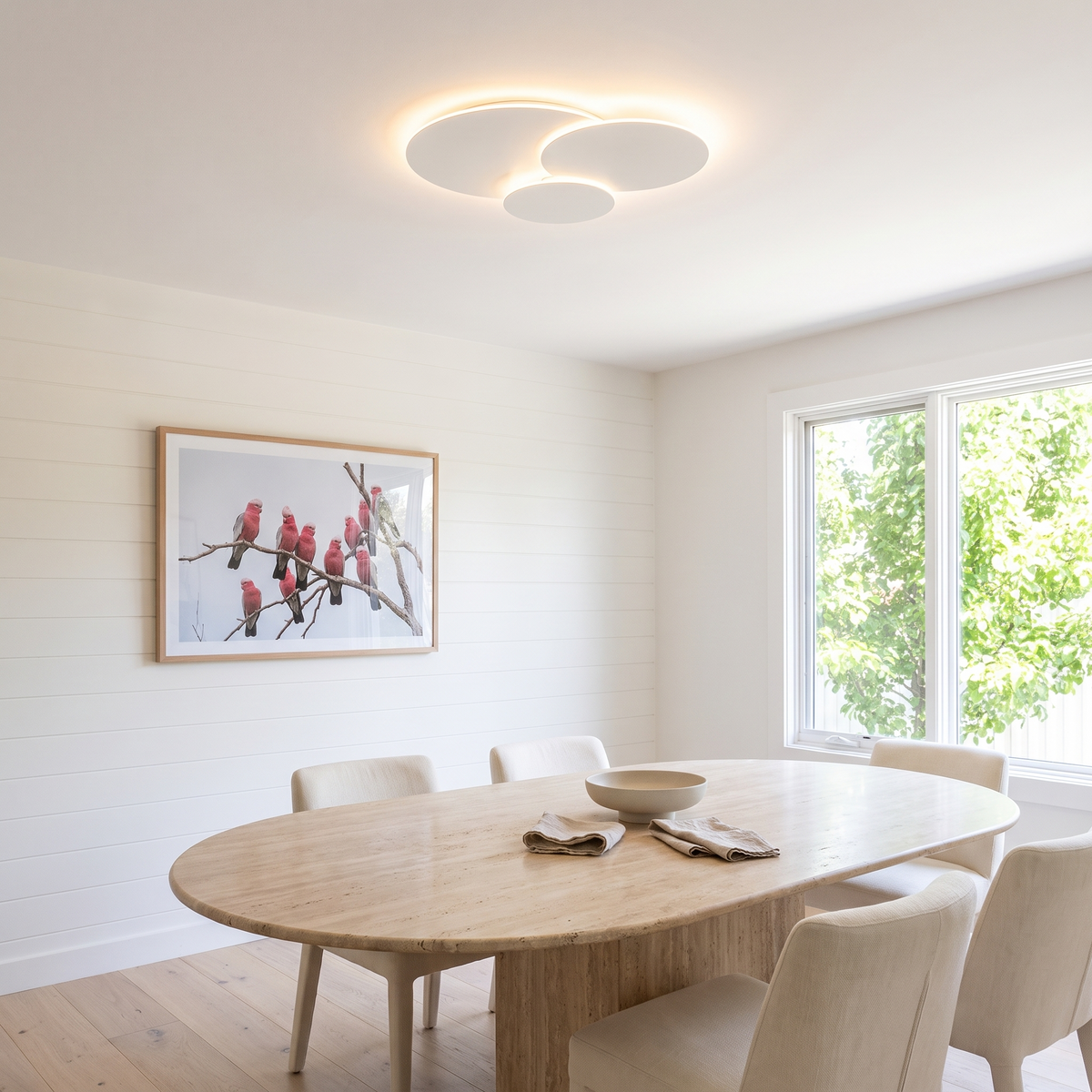 Cloey cloud disc LED ceiling light above a dining room with an oval travertine table