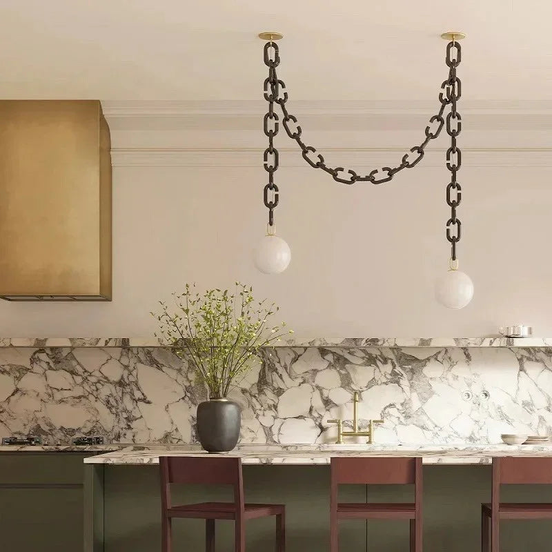Clove 2-head glass chain pendant light with brass fittings above a marble kitchen bench