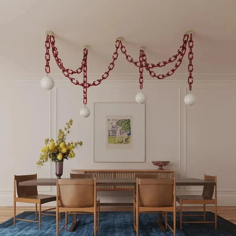 Clove 4-head red glass chain pendant light with white globe shades above a modern dining table