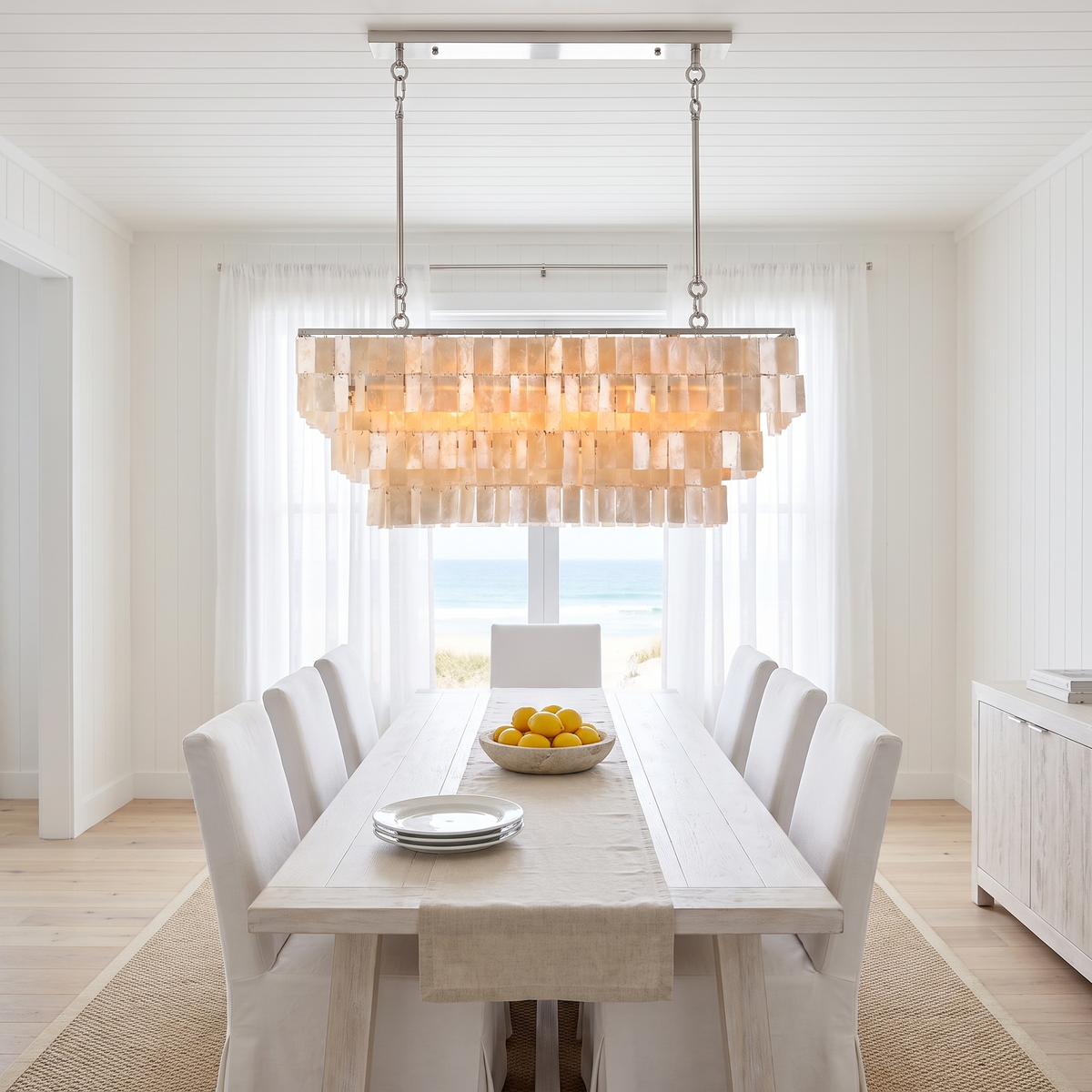 Coolum shell chandelier along a whitewashed dining table in a bright Hamptons beach house