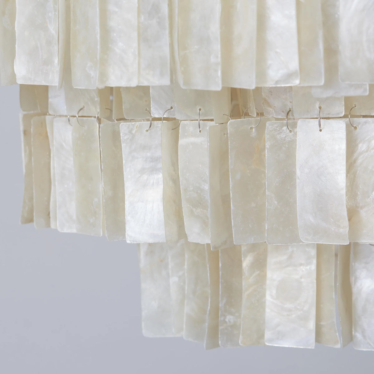 Close view of the Coolum chandelier's capiz shell tiles hung in rows on fine wire clips