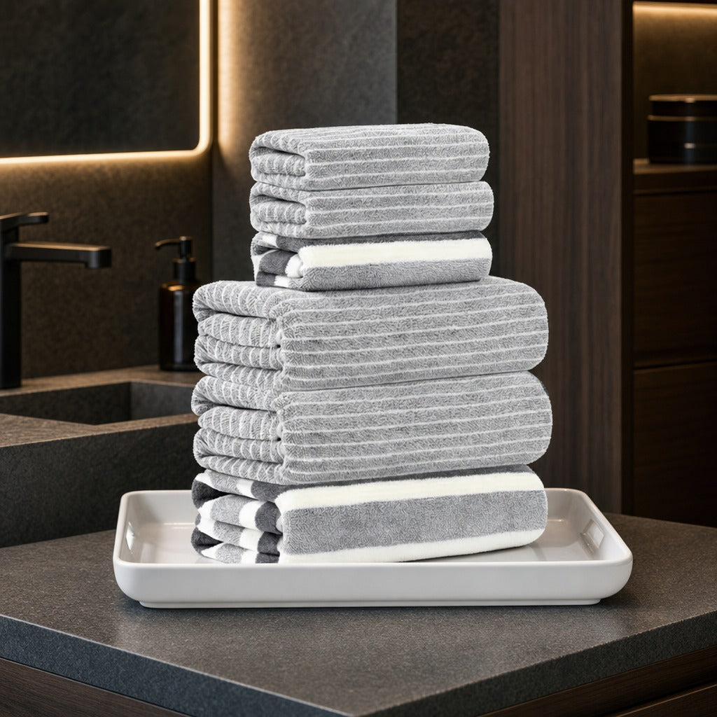 Coral fleece bath towel set in grey stripes on a white tray on a dark stone vanity