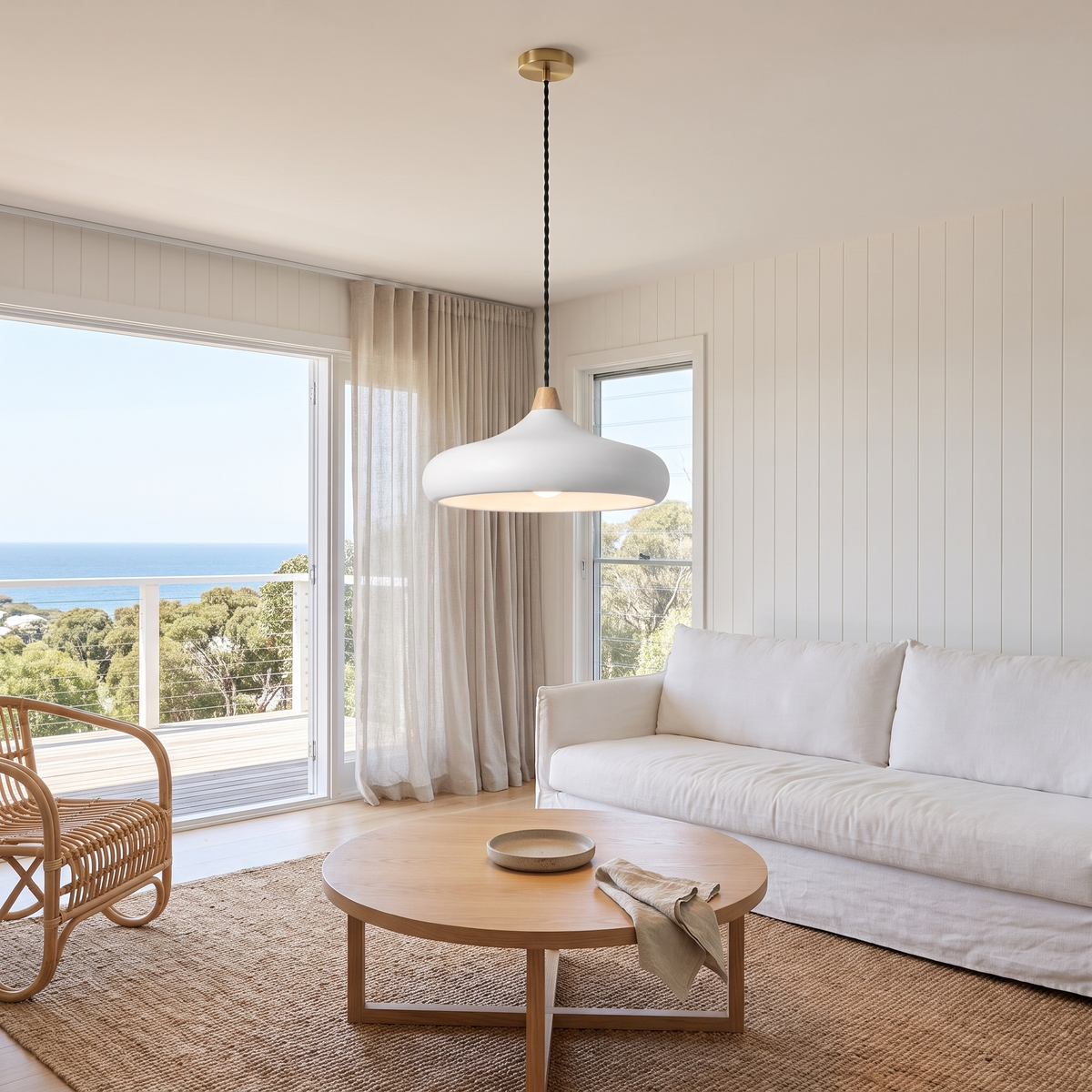 Dakota smooth white disc pendant light above a round oak coffee table in a beach house living room