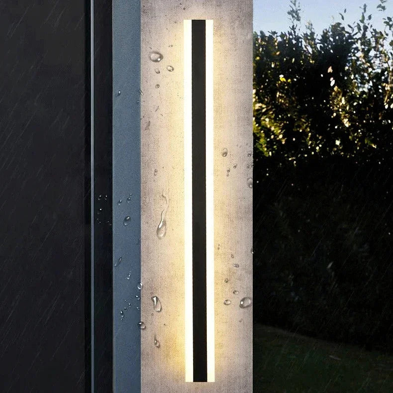 Daleh Iron LED Outdoor Wall Light illuminated at night on a courtyard wall