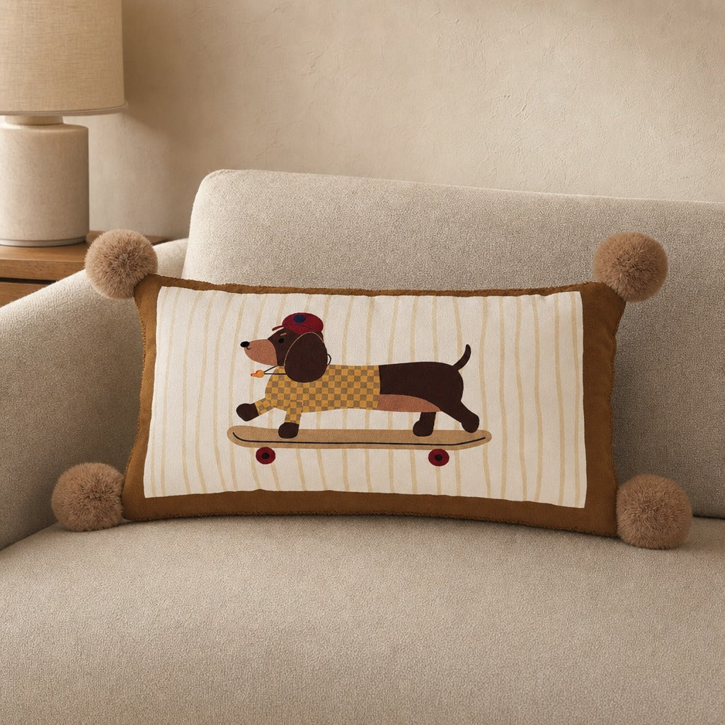 Dawg dog print lumbar throw pillow with a skateboarding dachshund and pom-pom tassels on a cream sofa