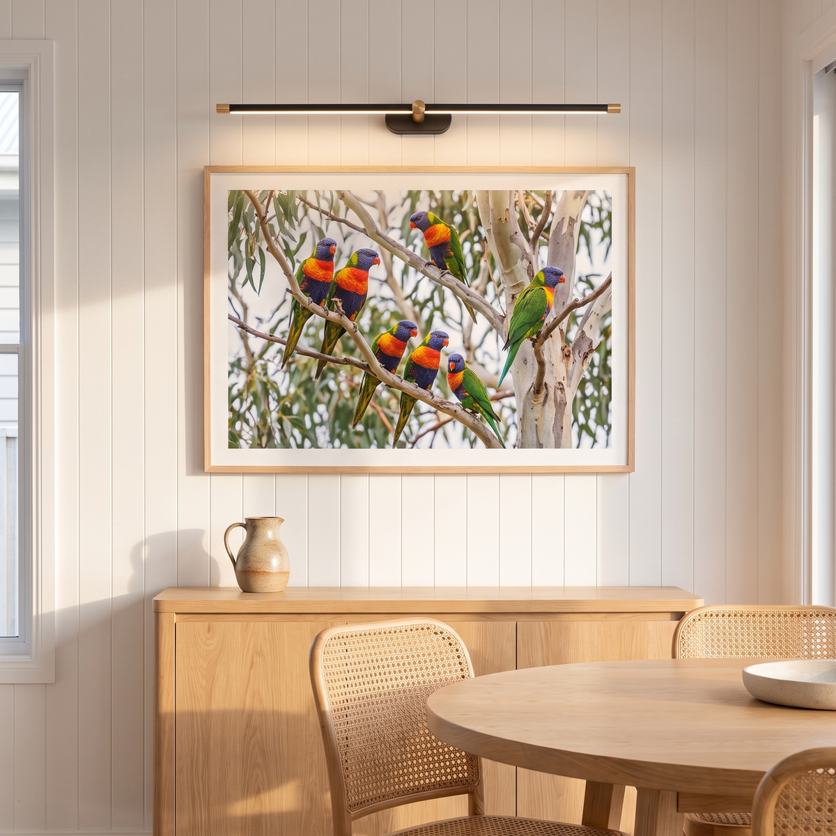 Debi black and gold wall lamp lighting a lorikeet print above an oak sideboard