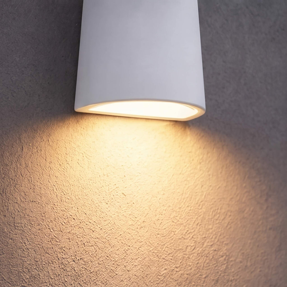 Dewy torch-style outdoor wall light in white casting a warm downward beam over a textured wall