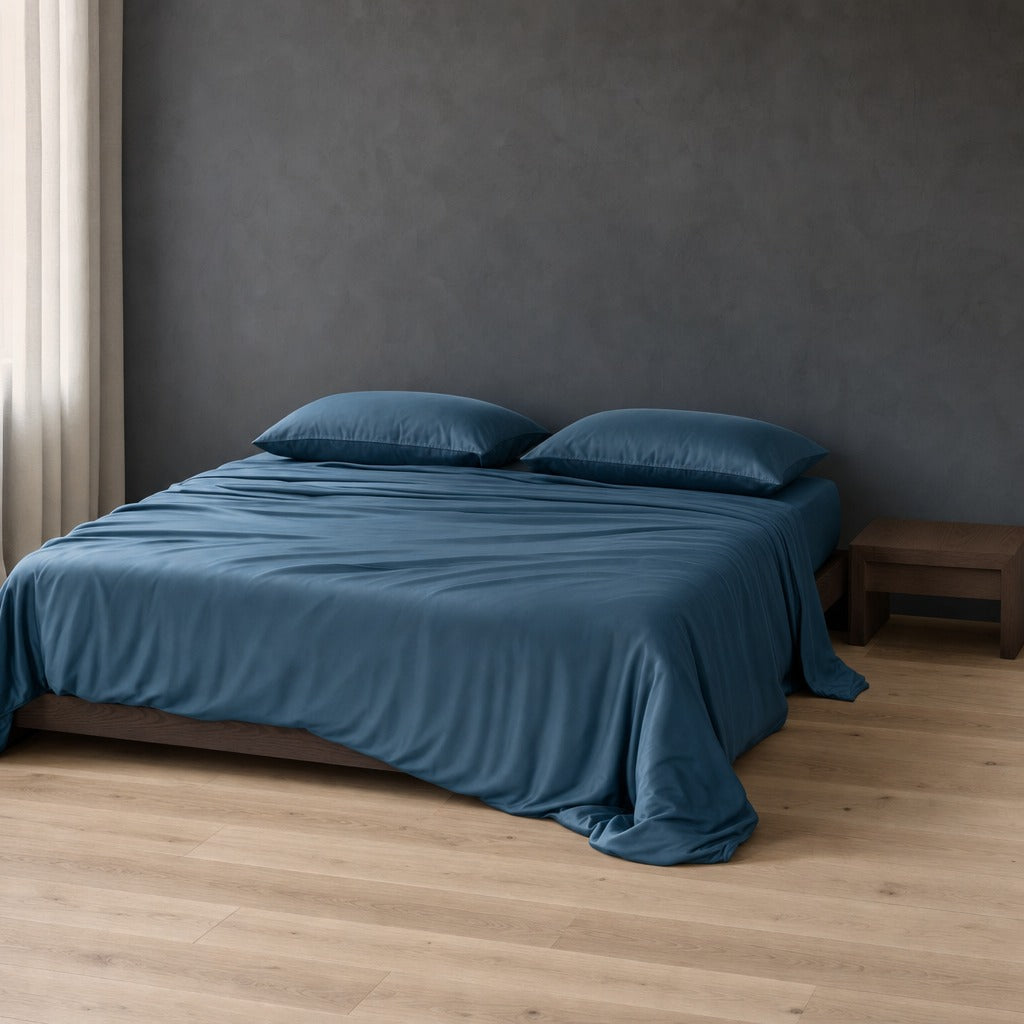 Eco Haven bamboo sheet set in blue on a timber bed against a charcoal wall