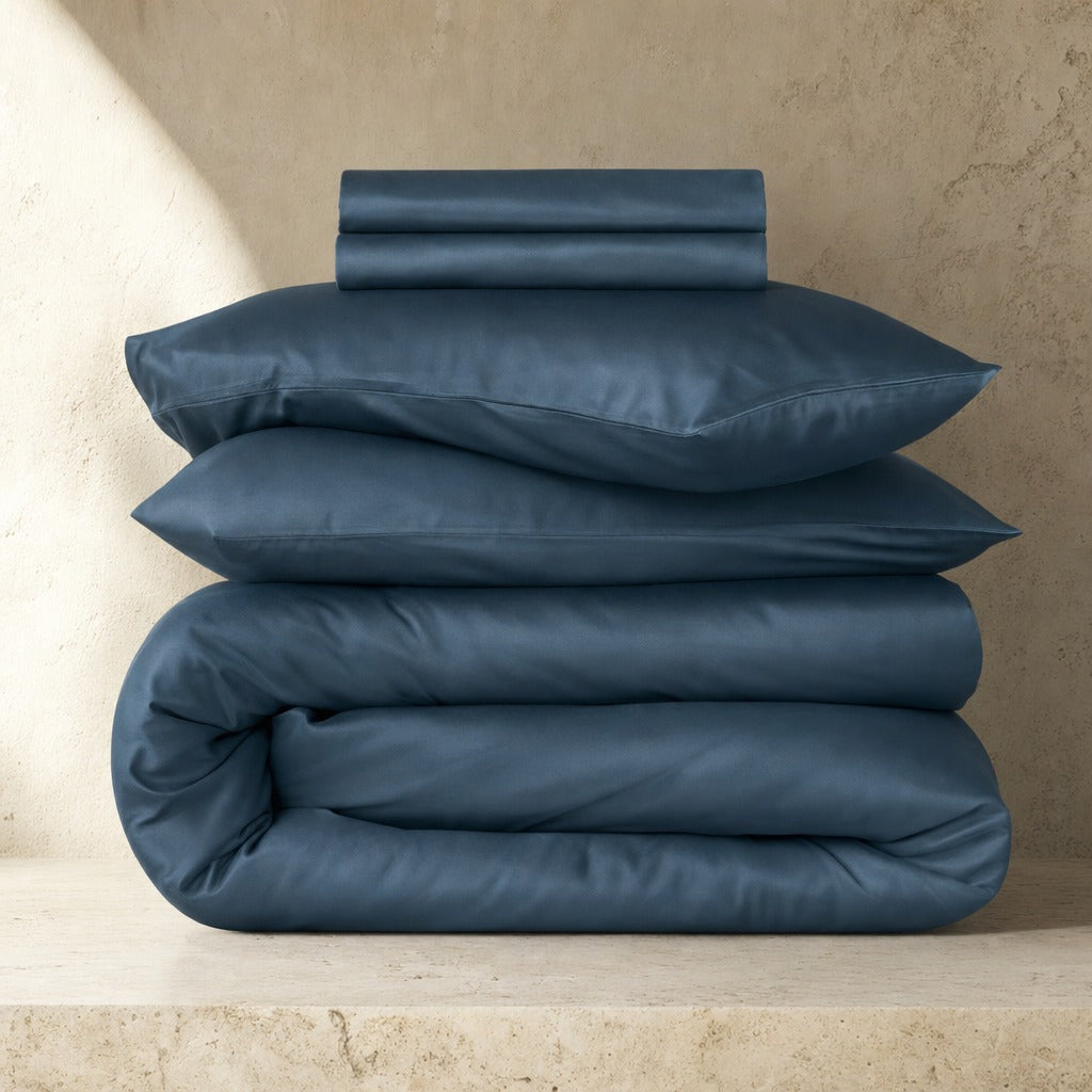 Eco Haven bamboo sheet set and duvet cover in blue folded on a stone plinth