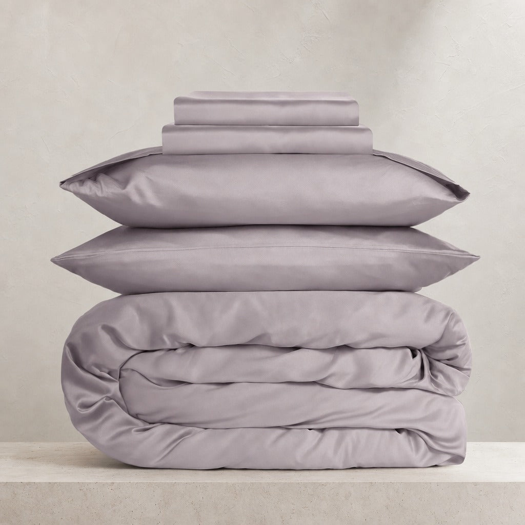 Eco Haven bamboo sheet set and duvet cover in purple folded on a stone ledge