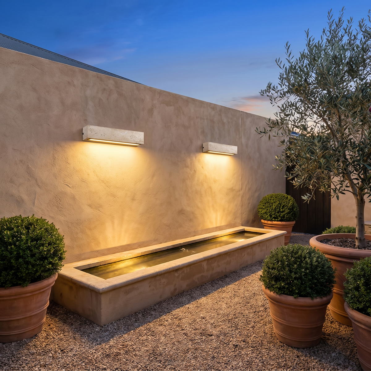 Two large Elin travertine wall lights on a courtyard garden wall above a water feature