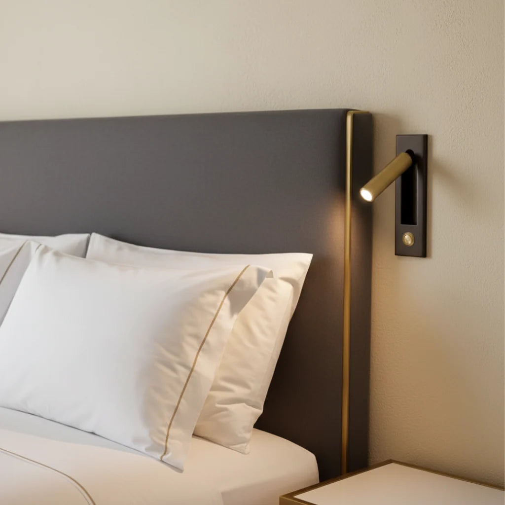 Espy LED reading wall light in black brass mounted beside an upholstered headboard