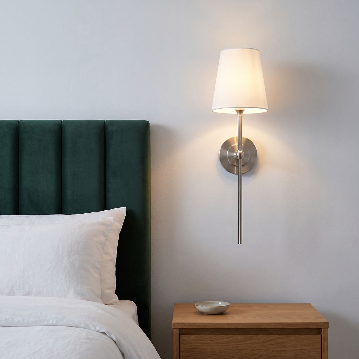 Tall Gini nickel wall sconce beside a green velvet headboard