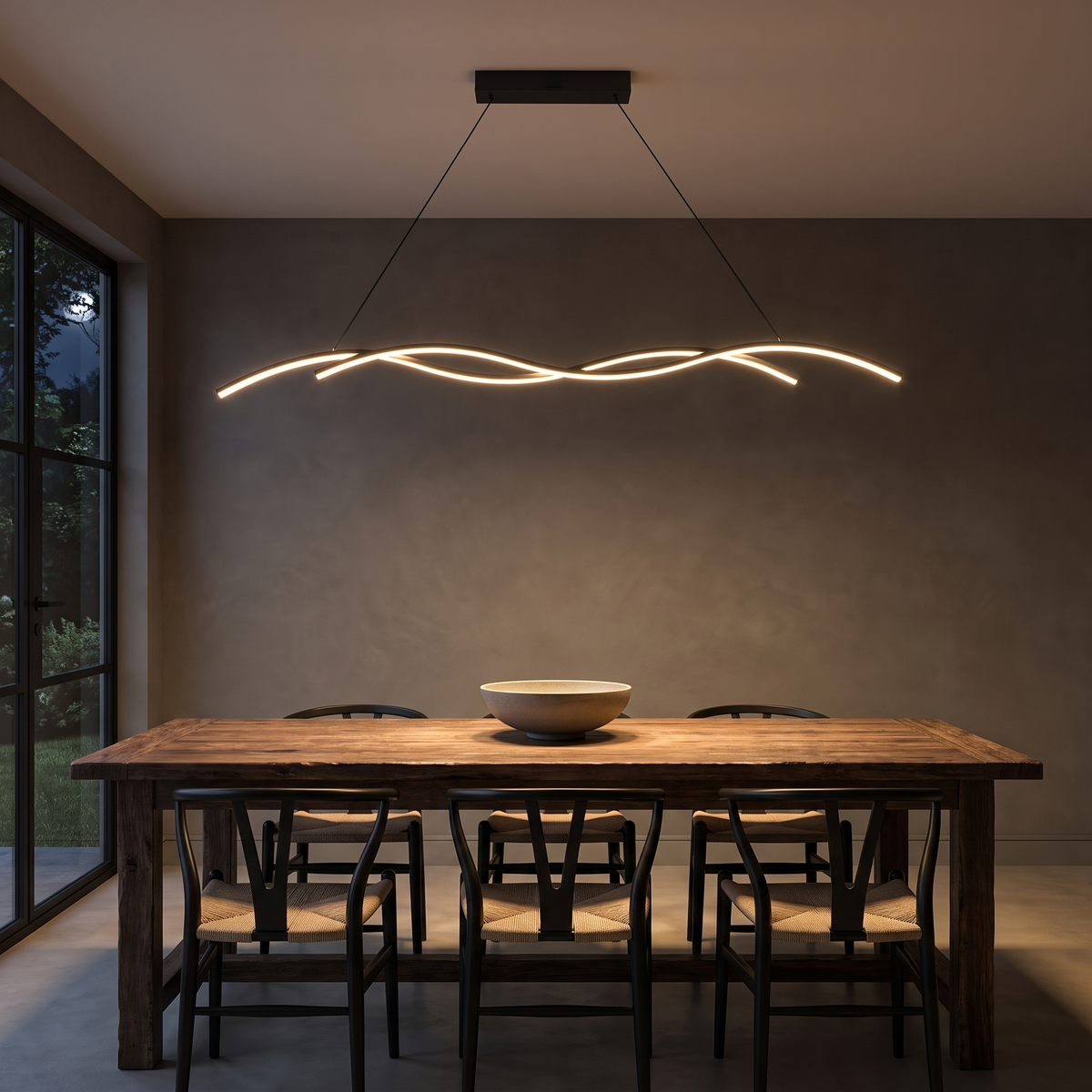 Grajagan black wave pendant glowing over a rustic timber dining table at night