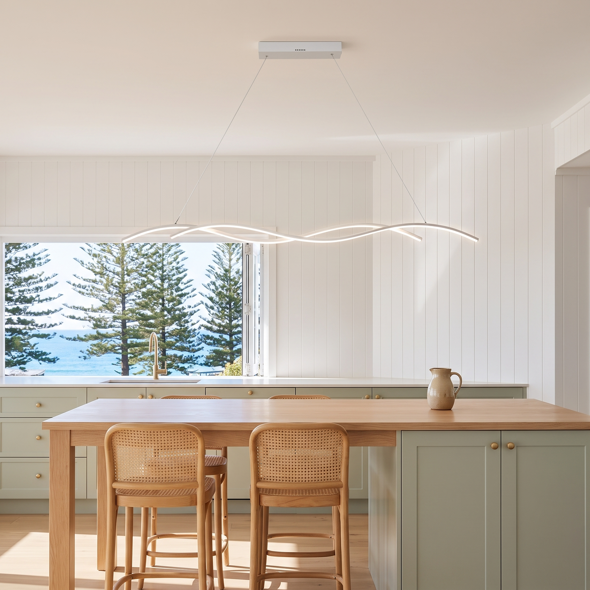 Grajagan white wave pendant above an oak kitchen island with Norfolk pines and ocean view