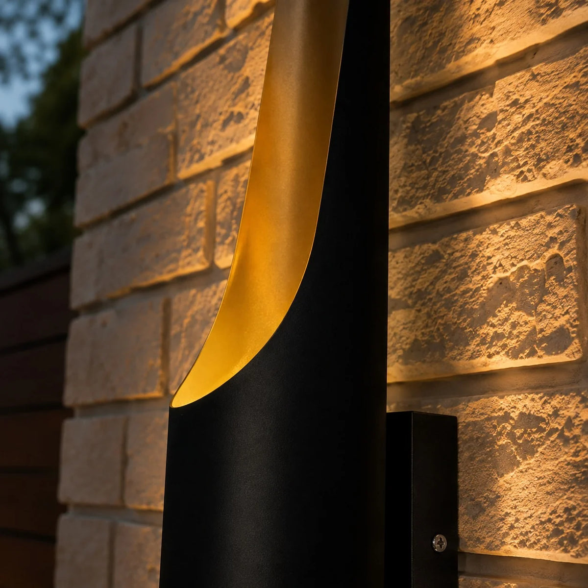 Close-up of a Jarra tube's angled end showing the gold interior washing light over a brick wall