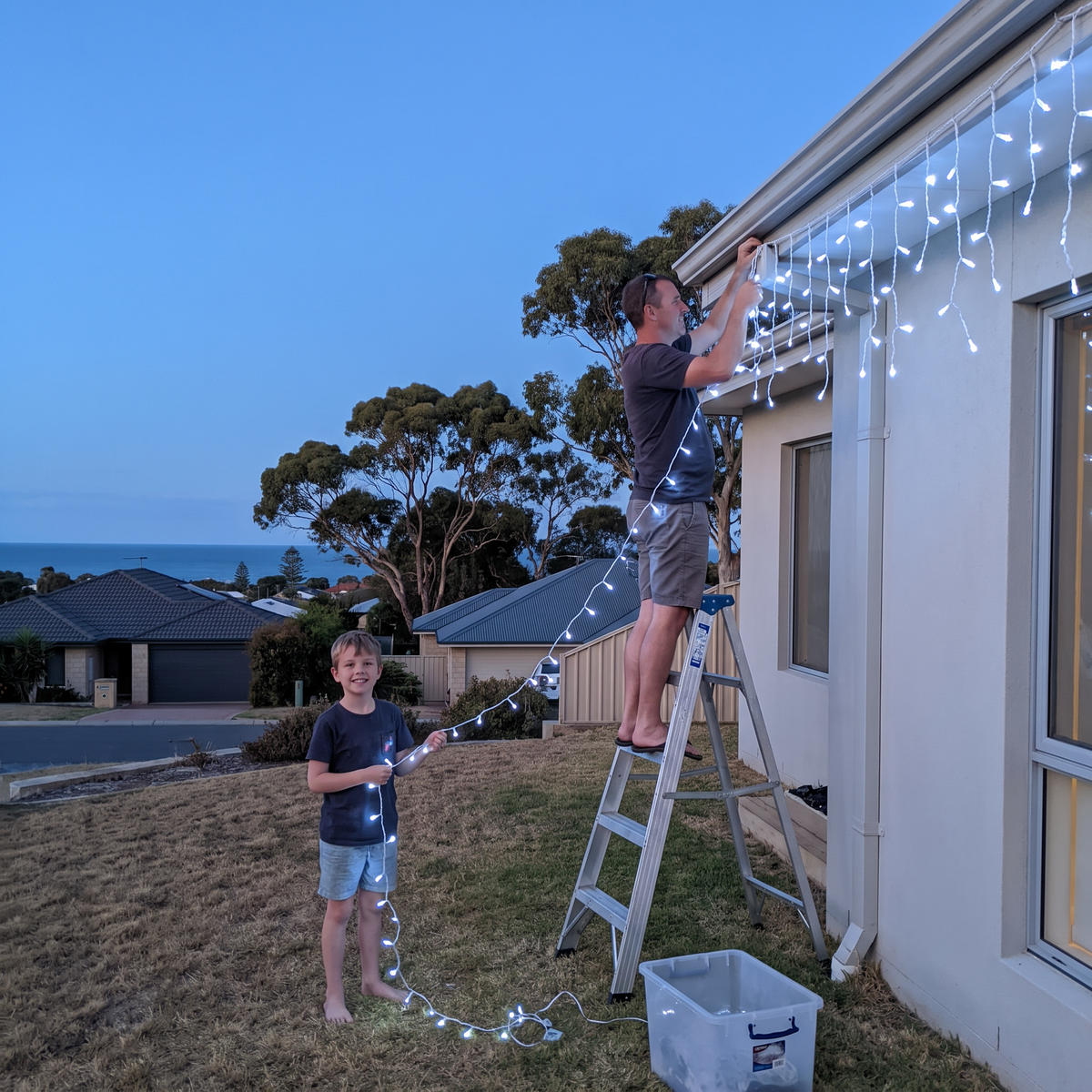 Hanging Jingle LED icicle lights in cold white on a house gutter at blue hour