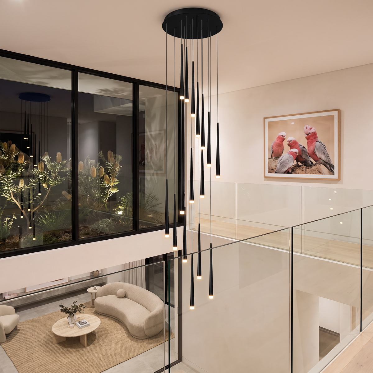 Black Jundaru pendant light hanging high in a double-height living room void, seen from the upper gallery