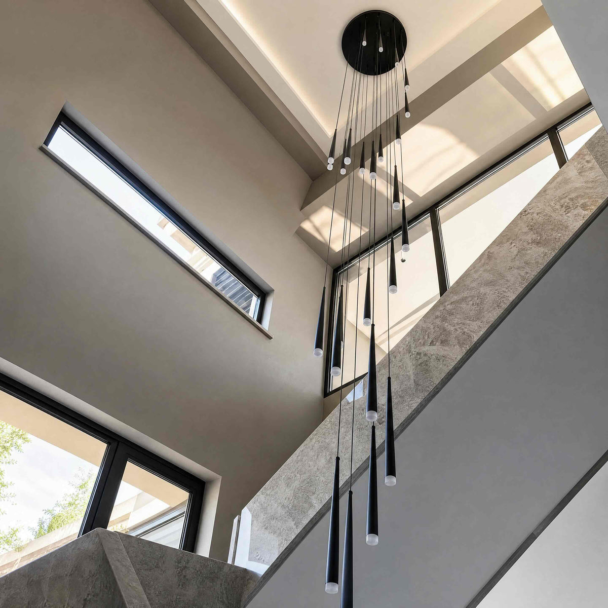 Black Jundaru cluster pendant hanging beneath a skylight in a tall stair void