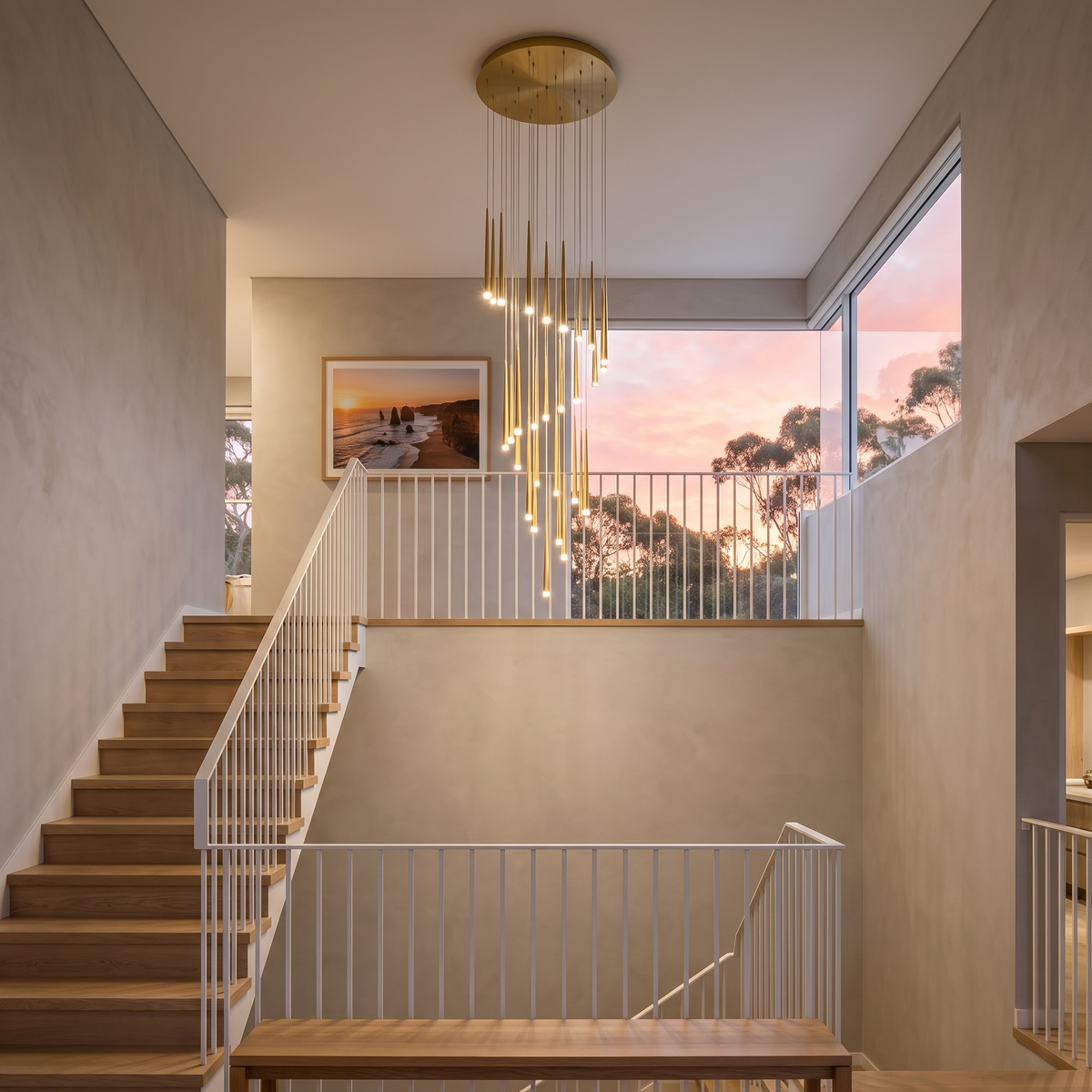 Gold Jundaru cluster pendant hanging high above a double-height oak staircase at dusk