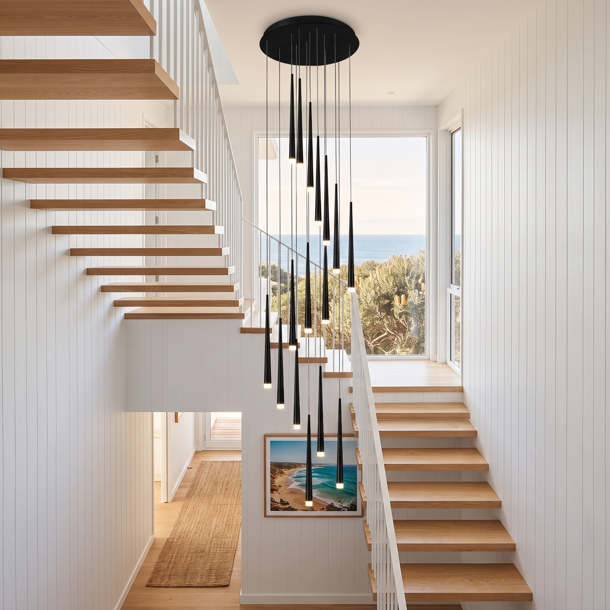 Jundaru pendant light in black hanging down a white shiplap beach house stairwell with an ocean view