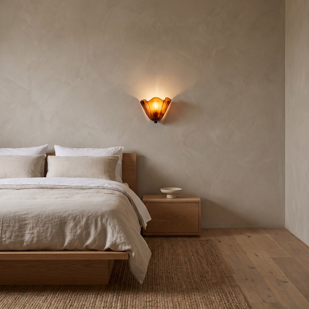 Kira artistic wall sconce in brown glass lit above an oak bedside in a Scandinavian bedroom